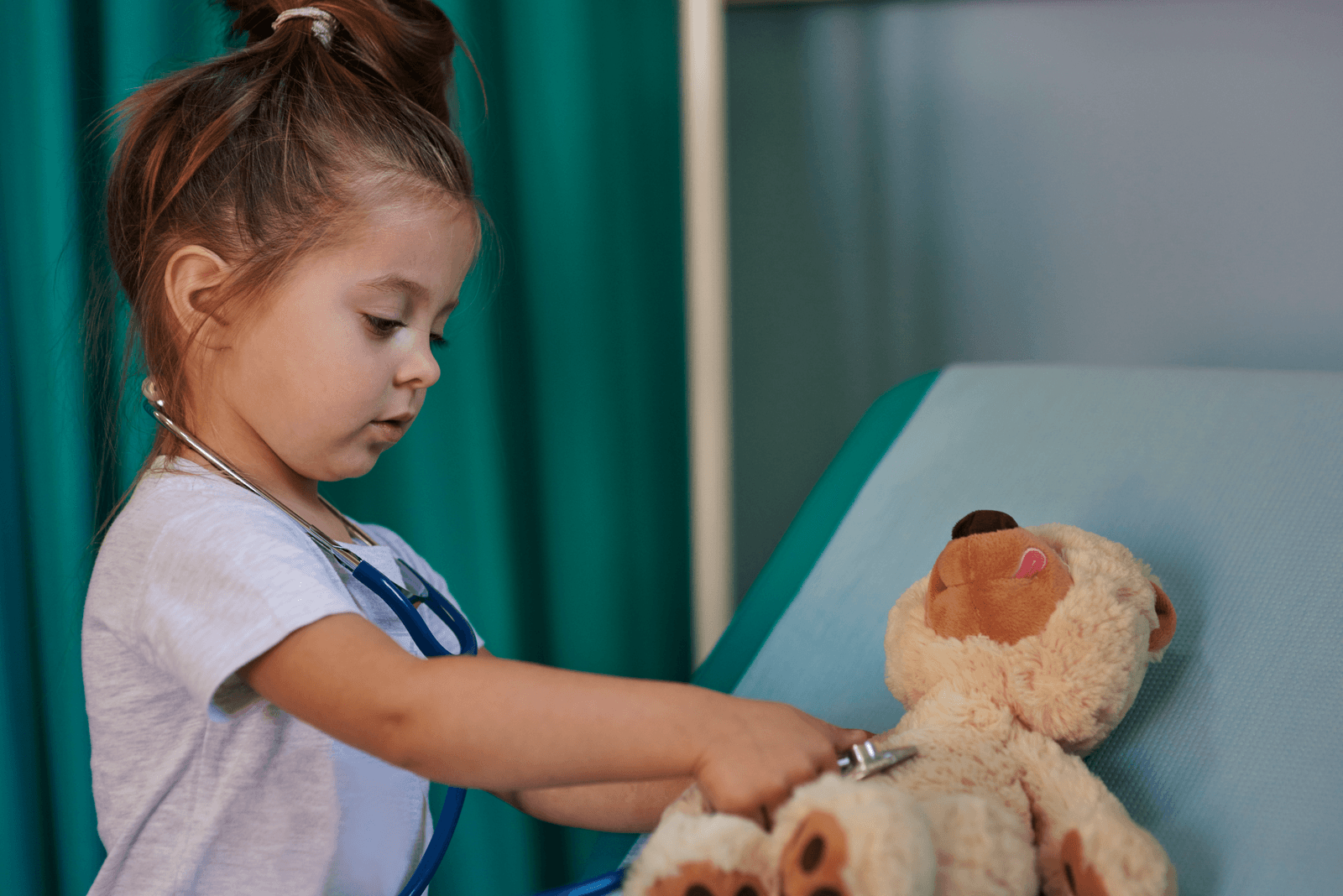 Kind hört mit dem Stethoskop einen Teddybären ab
