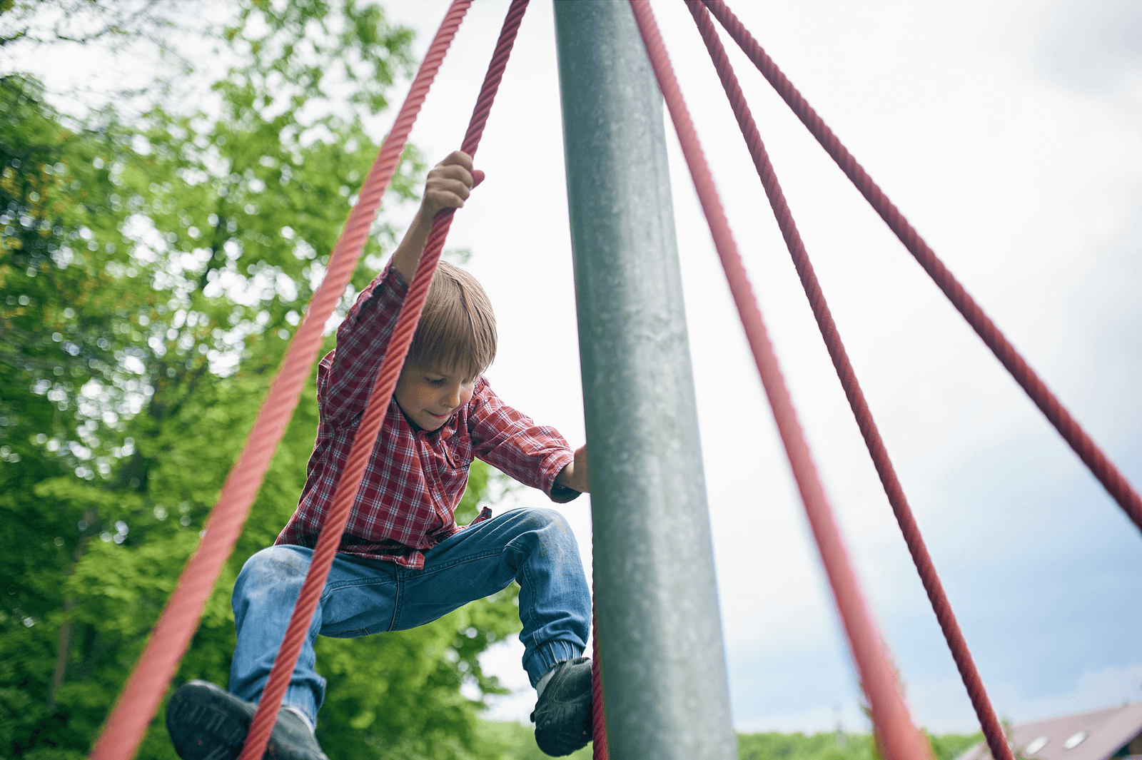 Kind klettert auf einem Spielplatz-Klettergerüst