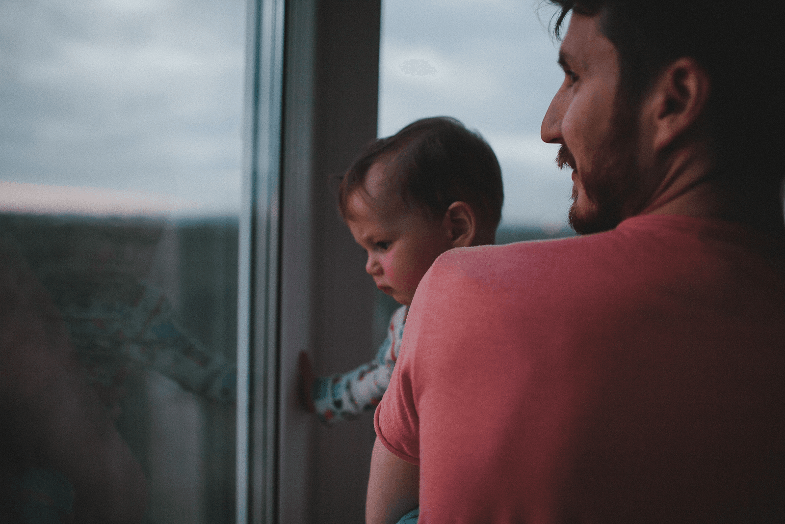Elternteil und Kind blicken gemeinsam aus dem Fenster